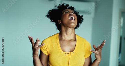 Фотография One frustrated young black woman screaming in despair at sky gesturing with hand