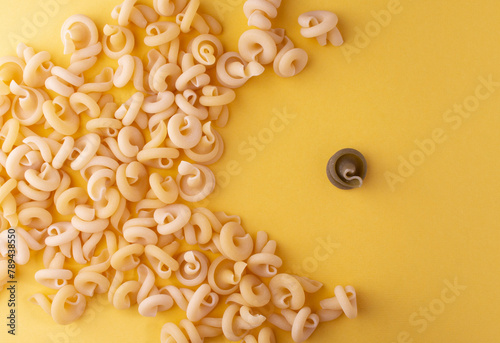 Raw insalatonde pasta on a yellow background. Natural and green pasta. One green and a lot of natural-colored pasta. Close-up. Тор View. Flatlаy photo