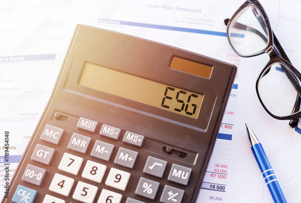 A calculator with ESG displayed, alongside financial papers, signifies a focus on sustainable investments. A calculator with ESG displayed, alongside financial papers, signifies a focus on sustainable investments.