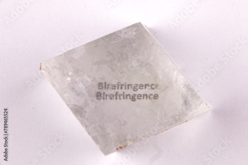 Optical birefringence demonstrated using a text using a natural double spar / calcite crystal photo