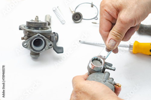 The man is repairing the carburetor of the car.