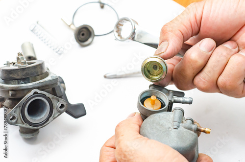 The man is repairing the carburetor of the car.
