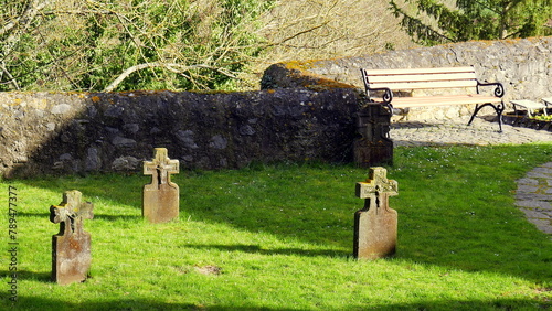 alte Steinkreuze auf dem Friedhof der Kirche in Dietkirchen im grünen Gras im Sonnenschein