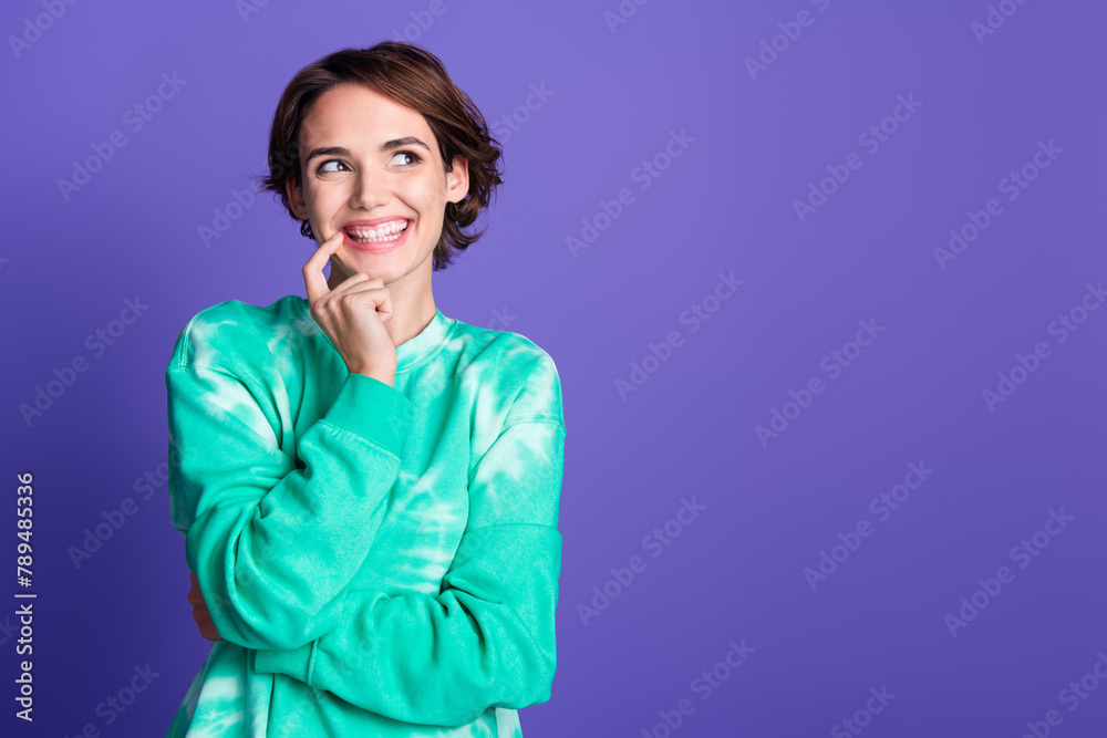 Photo of attractive young woman touch chin cheerful look empty space dressed stylish green clothes isolated on violet color background Photo of attractive young woman touch chin cheerful look empty space dressed stylish green clothes isolated on violet color background