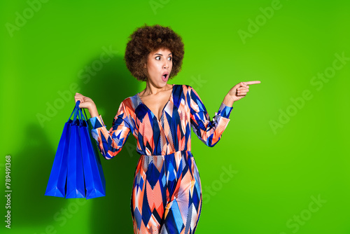 Photo of schocked charming glad woman wear trendy print clothes recommend boutique empty space isolated on green color background photo