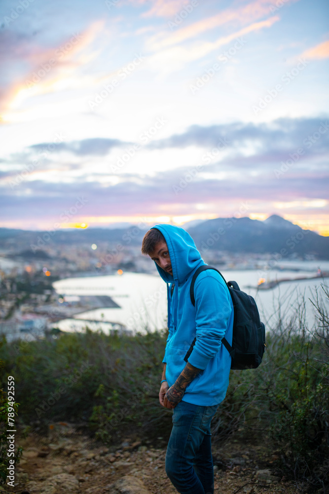 A male backpacker gazes into a valley surrounded by the bay of Ceuta