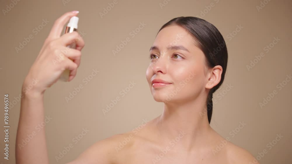 Droplets in Super slow motion. Young woman sprays a facial spray mist or thermal water, soothing tonic. Toning, moisturizing, soothing facial skin. Beauty treatment. Slow motion