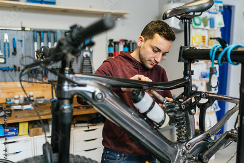 Bike mechanic manipulates the suspension system of an electric mountain bike using a ratchet wrench.