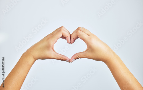 Hands  closeup and person in studio with heart sign  gesture or symbol isolated on white background. Zoom  love and care icon with romance emoji for compassion  kindness and happiness for valentines