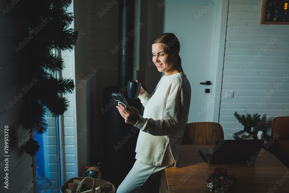 Home of young woman studying and drinking coffee while sitting at table with laptop and laptop at home - obrazy, fototapety, plakaty 