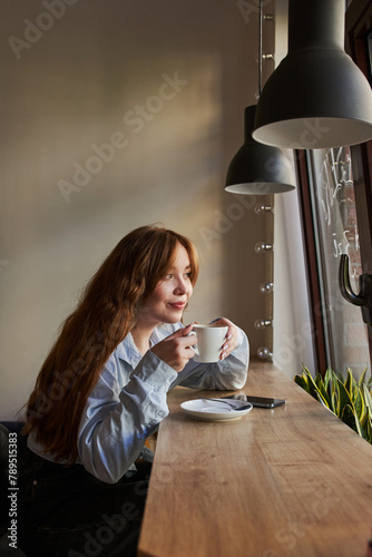 Young red-haired woman drinking coffee