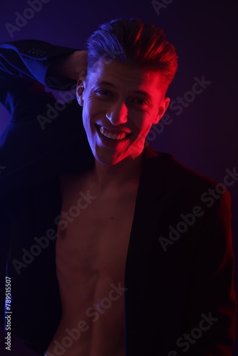 Sexy young man on dark background in neon lights