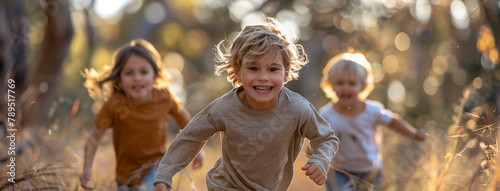 A group of small children in blurred background and one cute little boy smiling and running in front of the camera 
