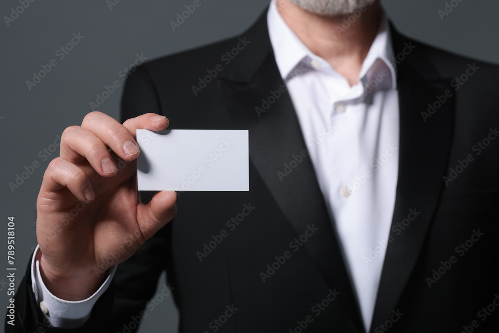 Man holding blank business card on grey background, closeup Man holding blank business card on grey background, closeup