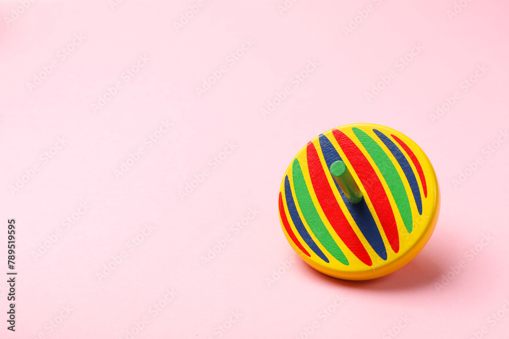 One colorful spinning top on pink background, space for text