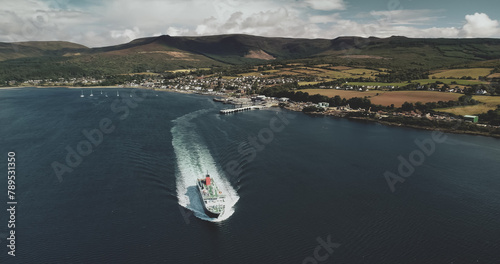 Scotland's ocean, passenger ferry aerial view in coastal water of Firth-of-Clyde Gulf. Ship crossing from Brodick terminal to Scottish mainland. Cityscape at green valleys. photo