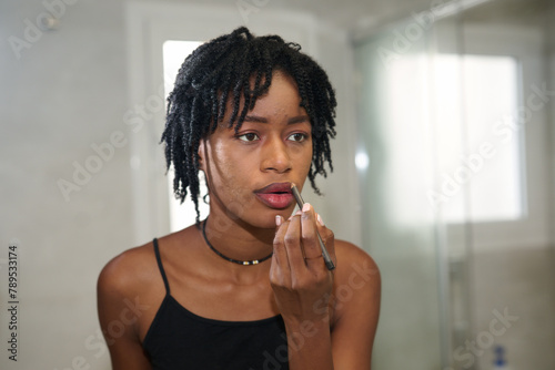 Afro woman applying lipstick photo