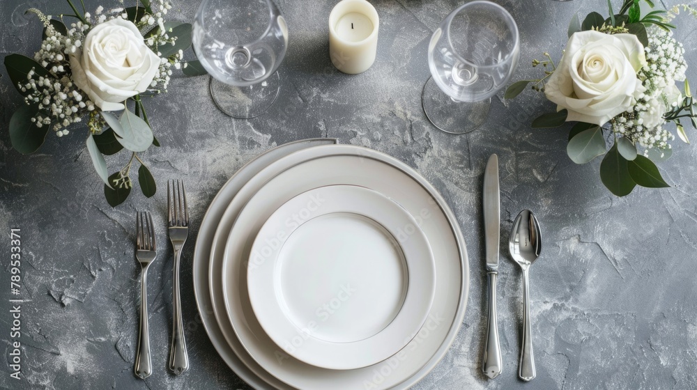 Formal table setting with elegant white plates and floral decoration on a textured grey background. Formal table setting with elegant white plates and floral decoration on a textured grey background.