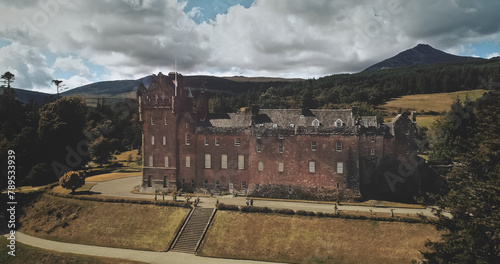 Scotland Brodick Castle aerial front shot: heritage of Scottish. Historical landmark of Arran Island with majestic landscape. Parks and garden near building under cloudy sky. Scenery view photo