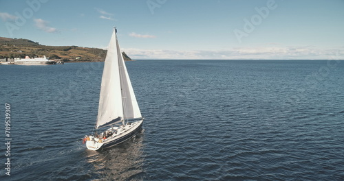 Closeup slow motion of sail boat at ocean gulf aerial. Racing yacht at sea bay. Majestic seascape at luxury sailboat at Brodick pier, Arran island shore, Scotland, Europe. Cinematic summer cruise