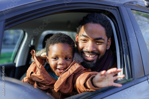 Portrait of father and son sitting on driver's seat in car