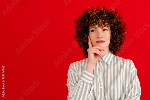 Thoughtful young woman touching chin with finger in studio