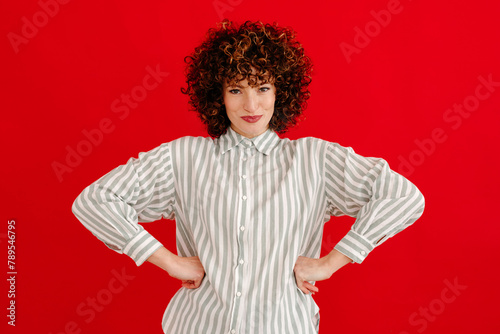 Happy curly haired woman with hands on waist looking at camera photo