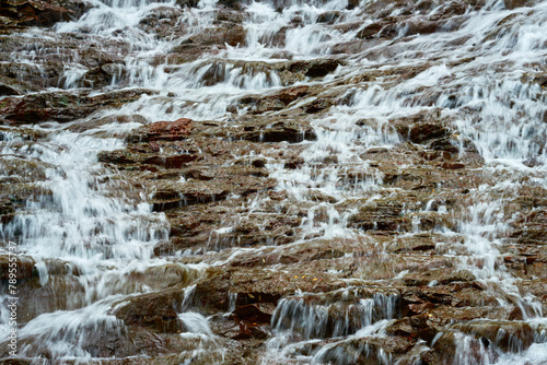 Water from the small mountain creek flows over the rocks.