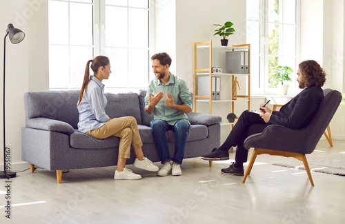 Working on relationships. Psychologist listens to conversation of married couple during therapy session. Couple sits on sofa and resolves conflict in therapy session. Concept of marital therapy.