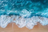 Pristine aerial shot of clear ocean waves lapping a sandy beach shoreline