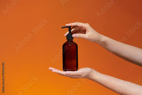 A woman is holding an amber soap bottle with both of hands photo