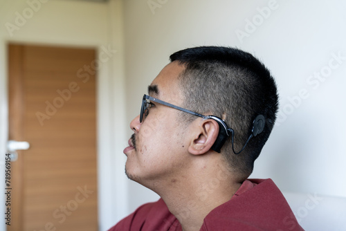 Young guy with a cochlear implant chilling at home photo