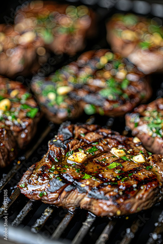 Steaks on the grill, brushed with olive oil and sprinkled with chopped garlic