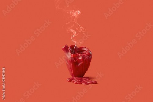 Blown out candle in shape of heart leaving drops of wax in red studio photo