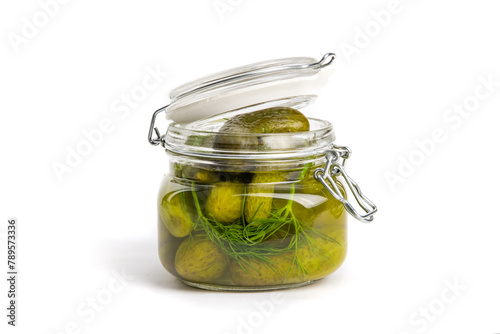 A glass home canning jar of baby dill pickles with the lid partly open isolated on white