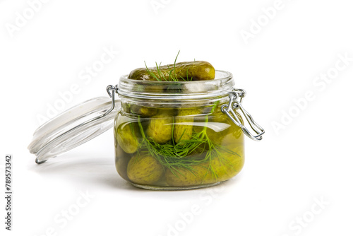 A glass home canning jar of baby dill pickles with the lid open isolated on white