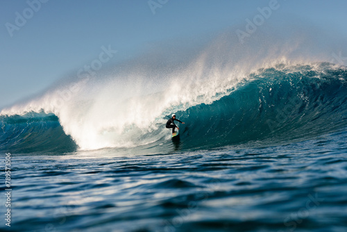 A young surfer joyfully rides a massive wave with his surfboard photo