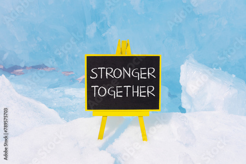 Stronger together symbol. Concept words Stronger together on beautiful yellow black blackboard. Beautiful blue ice background. Business, motivational and stronger together concept.