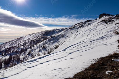 Scenic view of snow covered alpine meadow on hiking trail between Gertrusk and Ladinger Spitz, Saualpe, Carinthia, Austria, Europe. Hills landscape of Austrian Alps on moody cloudy early spring day photo