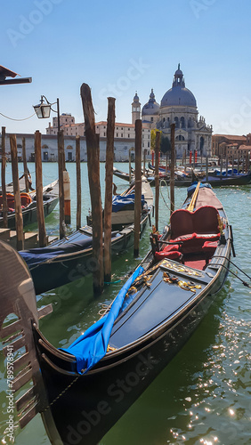 Group of gondolas moored by Saint Mark square in city of Venice, Veneto, Northern Italy, Europe. Scenic view of Santa Maria Della Salute cathedral. Romantic vacation in the Venetian Lagoon.