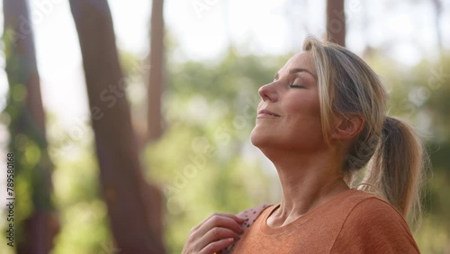 Mature woman on hike in countryside closing eyes and breathing deeply enjoying calm of nature - shot in slow motion