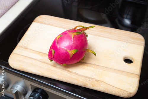 Whole pink fruit on wooden board. Sweet ripe dragon fruit. Exotic pitahaya tropical food.