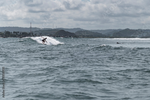 Surfer carving and riding surfboard in reef break wave photo