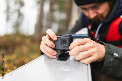 Man attaching action camera to kayak in wilderness adventure
