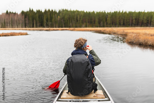 Young man rowing a kayak on a forest Lake photo
