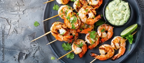 Grilled shrimp skewers with zesty lime marinade and accompanied by a creamy avocado cilantro garlic sauce. Displayed from a top view with copy space.