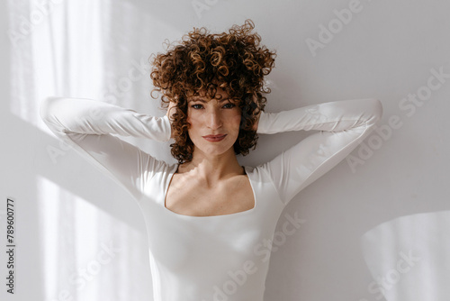 Female in square neck dress looking at camera while standing in studio photo