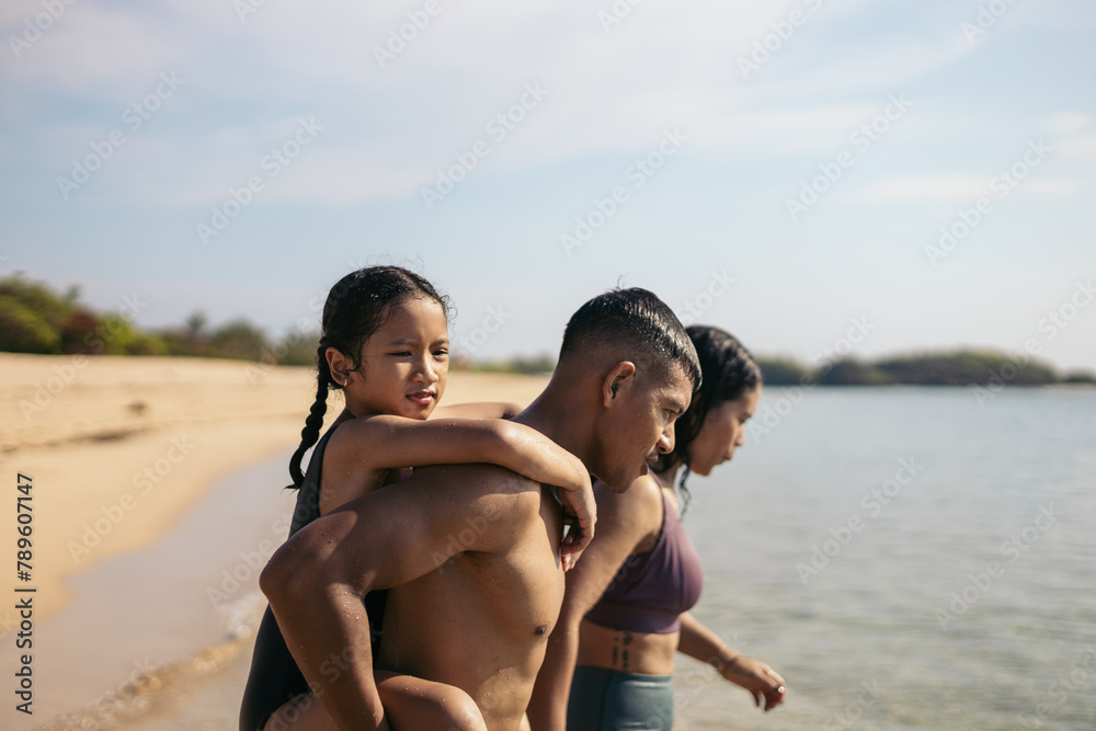Father giving his daughter piggyback on the beach Father giving his daughter piggyback on the beach