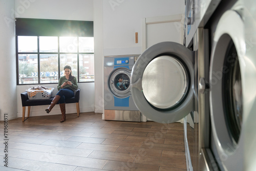 Woman waiting to wash her clothes in a laundromat photo
