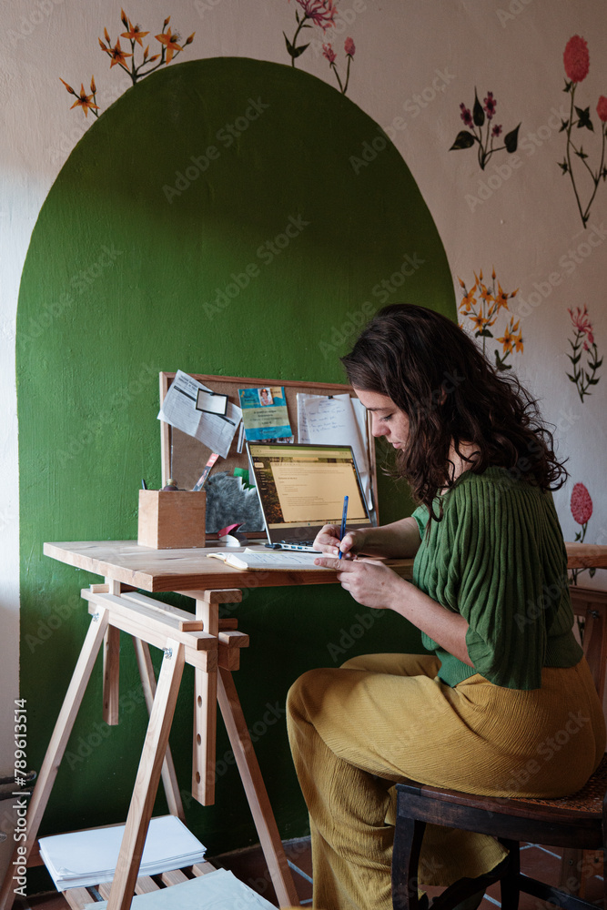 woman writing notes at her desk woman writing notes at her desk